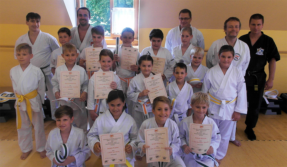 Foto: Kinder mit Urkunden und Kampfgericht nach den Gürtelprüfungen (Gruppenfoto)